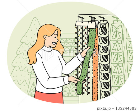 Woman chooses christmas decorations and garlands standing near store counter and new year tree 135244385