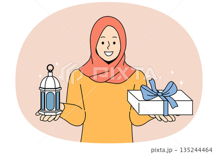 Muslim woman invites to celebrate ramadan, holy islamic holiday, holding gift box and lantern 135244464