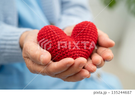 Asian elder senior woman patient holding red heart in hospital. 135244687