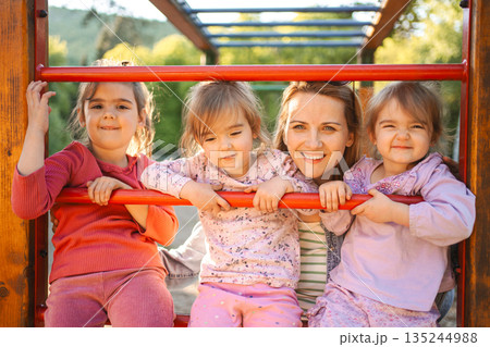 Smiling mom with daughters on the playground Smiling mom with daughters on the playground 135244988