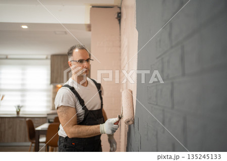 Man Painting Wall With Paint Roller Man Painting Wall With Paint Roller 135245133