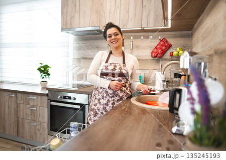 Happy woman wearing apron in the kitchen 135245193