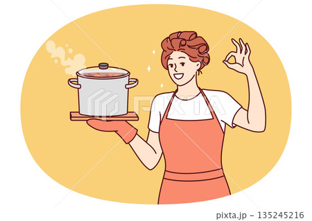 Woman housewife or cook with soup pan shows ok gesture and looks at screen smiling 135245216