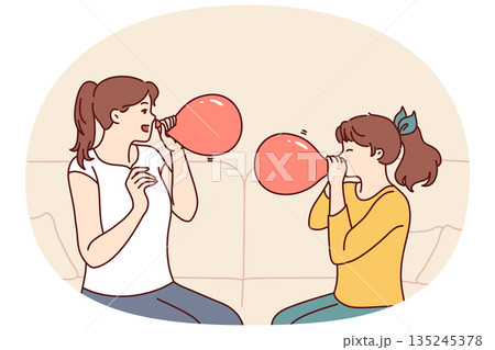 Mother and daughter inflate balloons sitting on sofa to decorate apartment for birthday party 135245378