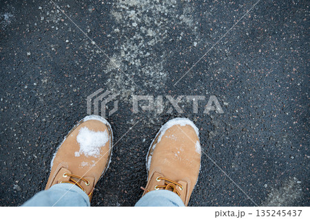 Anti-icing chemicals in winter. Top view of boots and asphalt strewn with technical salt or reagents Anti-icing chemicals in winter. Top view of boots and asphalt strewn with technical salt or reagents 135245437