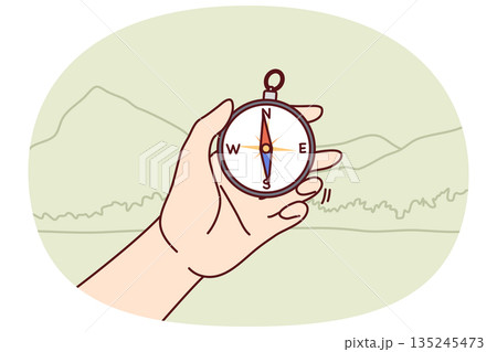 Compos in hand of person went on hike and determines direction of world to find way 135245473