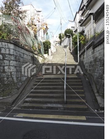 青空へと続く住宅街の長い階段。石垣に囲まれた奥行きのある坂道と冬の穏やかな日常風景。 青空へと続く住宅街の長い階段。石垣に囲まれた奥行きのある坂道と冬の穏やかな日常風景。 135245489