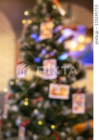 Softly lit Christmas tree with hanging photos and warm lights creating a cozy family holiday scene Softly lit Christmas tree with hanging photos and warm lights creating a cozy family holiday scene 135245713