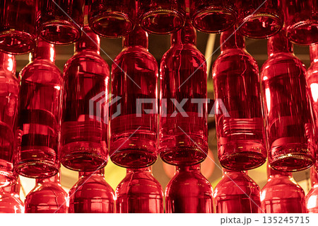 Vibrant red glass bottles hanging in a decorative arrangement creating a fiery visual display 135245715