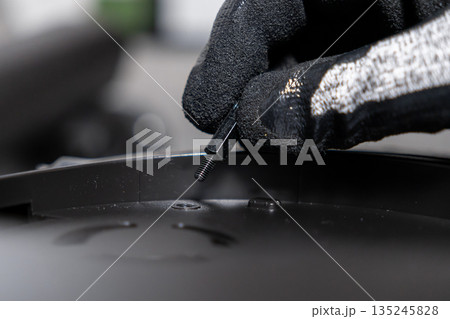 Professional technician wearing a protective glove carefully installs a standoff screw into an electronic component, depicting meticulous computer assembly and precise maintenance work 135245828