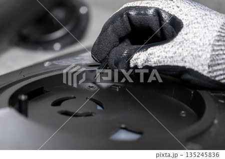 Professionals gloved hand precisely inserting a small screw standoff into a complex black electronic component, showcasing meticulous assembly and technical service Professionals gloved hand precisely inserting a small screw standoff into a complex black electronic component, showcasing meticulous assembly and technical service 135245836