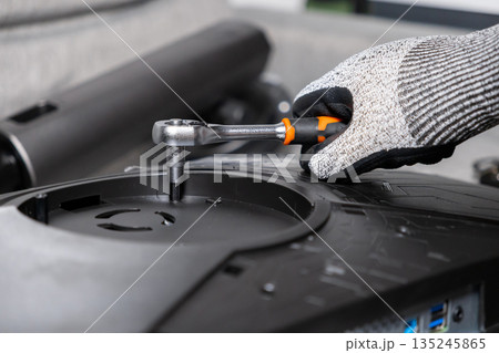 Gloved hand meticulously using a ratchet wrench to assemble a modern computer monitor, symbolizing professional repair and technical service Gloved hand meticulously using a ratchet wrench to assemble a modern computer monitor, symbolizing professional repair and technical service 135245865