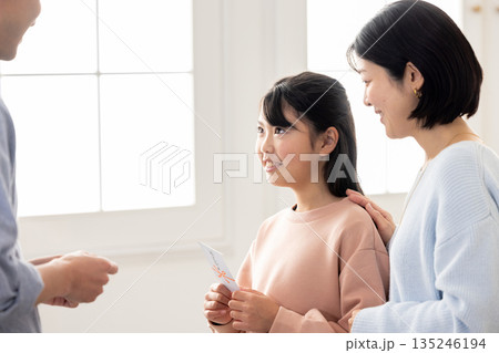 男性からお年玉をもらう小学生の女の子 男性からお年玉をもらう小学生の女の子 135246194