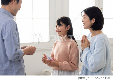 男性からお年玉をもらう小学生の女の子 男性からお年玉をもらう小学生の女の子 135246196