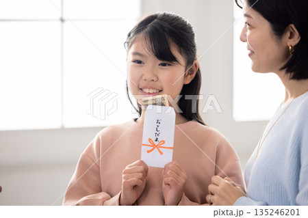 お年玉の中身を確認して微笑む小学生の女の子 お年玉の中身を確認して微笑む小学生の女の子 135246201