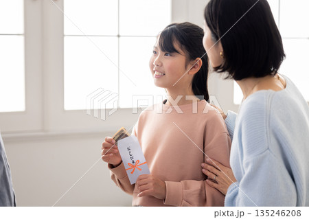 お年玉の中身を確認して微笑む小学生の女の子 135246208