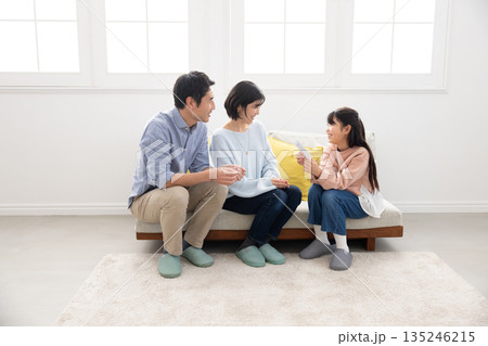 両親からお年玉をもらって微笑む小学生の女の子 135246215