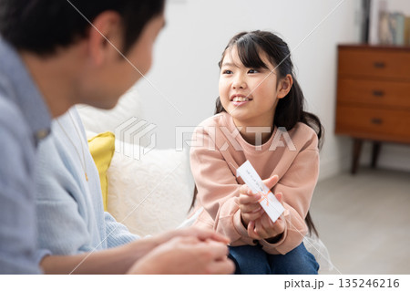 両親からお年玉をもらって微笑む小学生の女の子 135246216