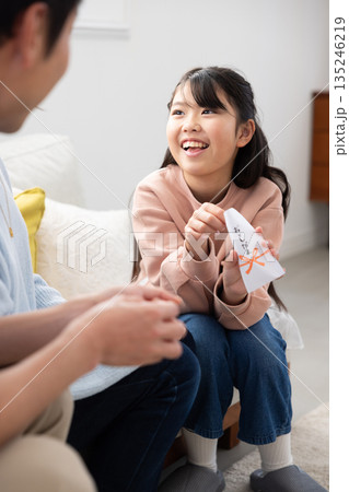 両親からお年玉をもらって微笑む小学生の女の子 135246219