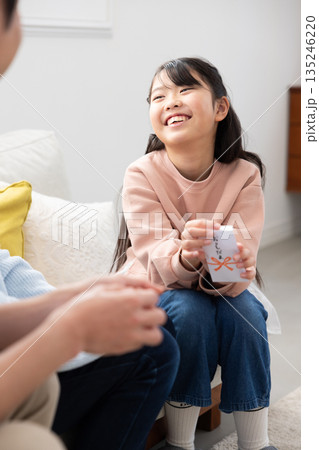 両親からお年玉をもらって微笑む小学生の女の子 両親からお年玉をもらって微笑む小学生の女の子 135246220