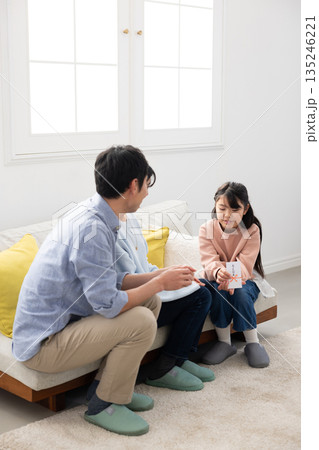 両親からお年玉をもらって微笑む小学生の女の子 両親からお年玉をもらって微笑む小学生の女の子 135246221