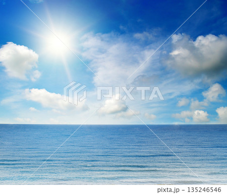 Serene ocean landscape under a bright sun and blue sky. Serene ocean landscape under a bright sun and blue sky. 135246546