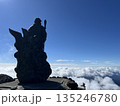 雲海を見下ろす山頂の守護像と青空 135246780