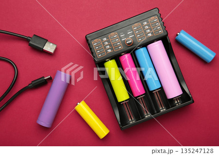 Rechargeable batteries in a battery charger. Four batteries in a charger. NI-MH and LI-MH battery. 135247128