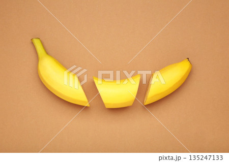 Cut banana, slices on light brown background. Minimalist concept. Cut banana, slices on light brown background. Minimalist concept. 135247133