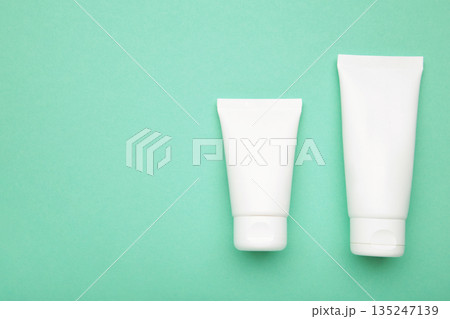White plastic cosmetic tubes on mint background. Space for text White plastic cosmetic tubes on mint background. Space for text 135247139