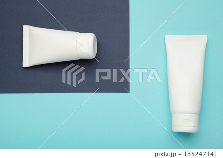 White plastic cosmetic tubes on blue background. Space for text 135247141