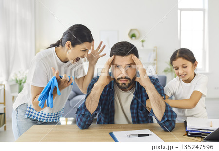 Stress and despair of father over chaos and noise at home, man sitting at table Stress and despair of father over chaos and noise at home, man sitting at table 135247596