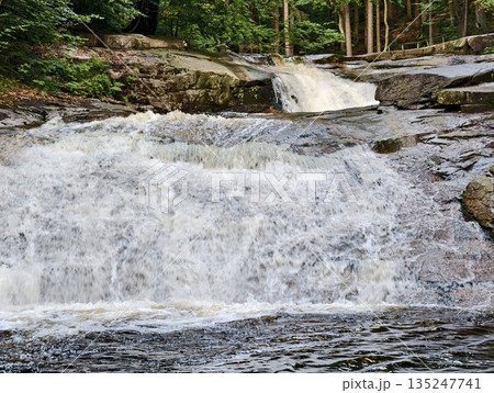 powerful waterfall on rocky ledge, majestic waterfall flowing over textured granite into wooded powerful waterfall on rocky ledge, majestic waterfall flowing over textured granite into wooded 135247741