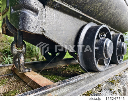 closeup of railcar wheel and chain, detailed closeup of rusted railcar wheel and surrounding 135247743