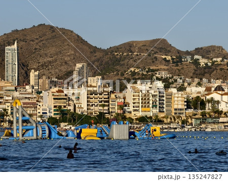 vibrant seaside water fun, lively summer scene with inflatable structures and swimming fun at sunset vibrant seaside water fun, lively summer scene with inflatable structures and swimming fun at sunset 135247827