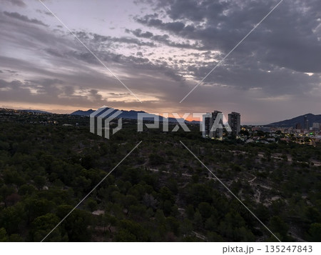 twilight over mountain suburbs, dusky atmosphere with mountain ridge and city lights in distance twilight over mountain suburbs, dusky atmosphere with mountain ridge and city lights in distance 135247843