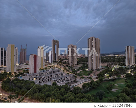 urban twilight with lit windows, serene evening view of city buildings and natural surroundings urban twilight with lit windows, serene evening view of city buildings and natural surroundings 135247846