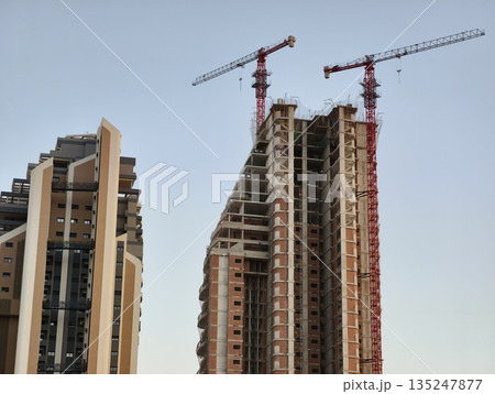 skyscraper rising with active cranes, progress of city skyline with construction equipment visible skyscraper rising with active cranes, progress of city skyline with construction equipment visible 135247877