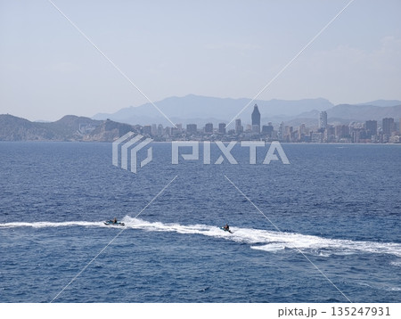 Vibrant summer scene featuring jet skis racing over blue water Vibrant summer scene featuring jet skis racing over blue water 135247931