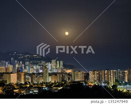 Evening scene featuring glowing buildings and distant mountain Evening scene featuring glowing buildings and distant mountain 135247949