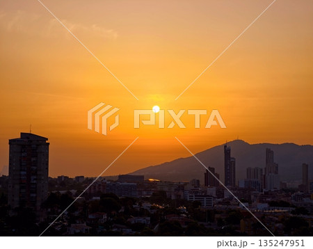Calm sunset scene featuring distant mountains and urban skyline 135247951