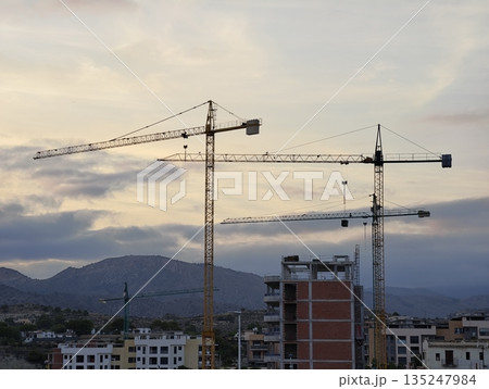 Dusk paints industrial structures against mountain backdrop 135247984