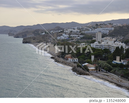 Serene evening by coast showcasing villas and gentle waves Serene evening by coast showcasing villas and gentle waves 135248000