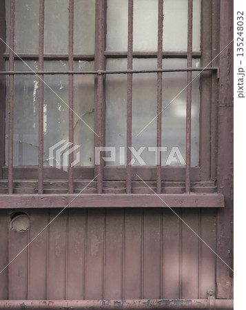 歳月に晒された空き家の窓と錆びた鉄格子。管理を離れ、静かに朽ちゆく日本の古い住宅の断片。 歳月に晒された空き家の窓と錆びた鉄格子。管理を離れ、静かに朽ちゆく日本の古い住宅の断片。 135248032