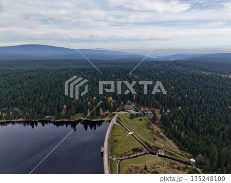 aerial perspective of tranquil water and dense forest with small dwellings and winding roads 135248100