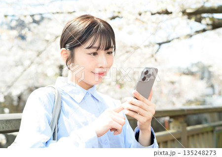 桜の木の下でスマホを使用する女性 135248273
