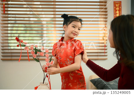 Mom and daughter decorated red apricot blossom with ornament for Chinese New Year Mom and daughter decorated red apricot blossom with ornament for Chinese New Year 135249005