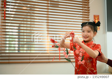 Mom and daughter decorated red apricot blossom with ornament for Chinese New Year 135249007