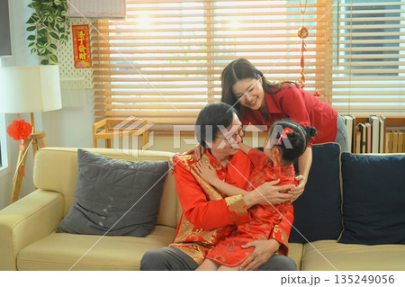 Grandfather hugs his granddaughter with love while celebrating Chinese New Year together in a warm and peaceful family home 135249056