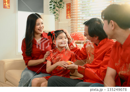 Young girl gives oranges to her grandfather and receives a red envelope, Chinese New Year 135249078